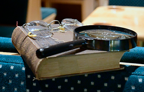 Altes Buch, Brille und Lupe liegen auf einem Sitz in historischer Straßenbahn.