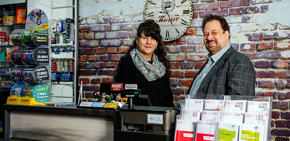 Frau und Mann stehen hinter einem Verkaufstresen in einem Zeitungsladen.