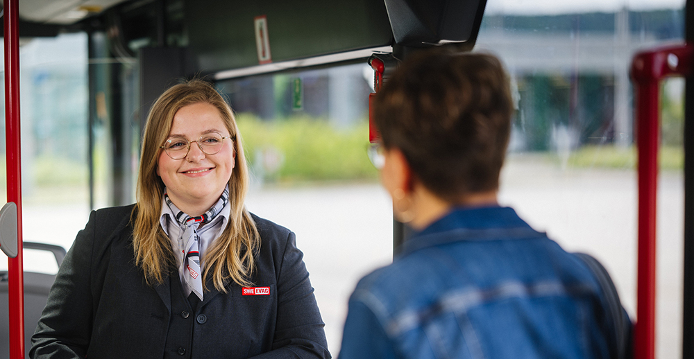 Busfahrerin lächelt einsteigenden Fahrgast an.