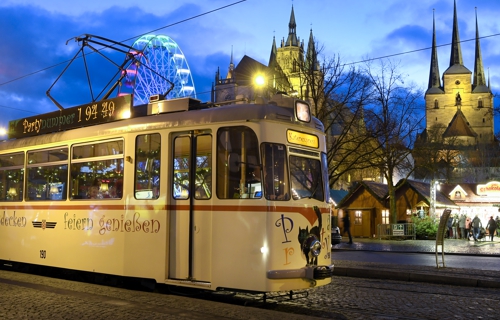 Historische Straßenbahn vor weihnachtlich geschmücktem Domplatz.